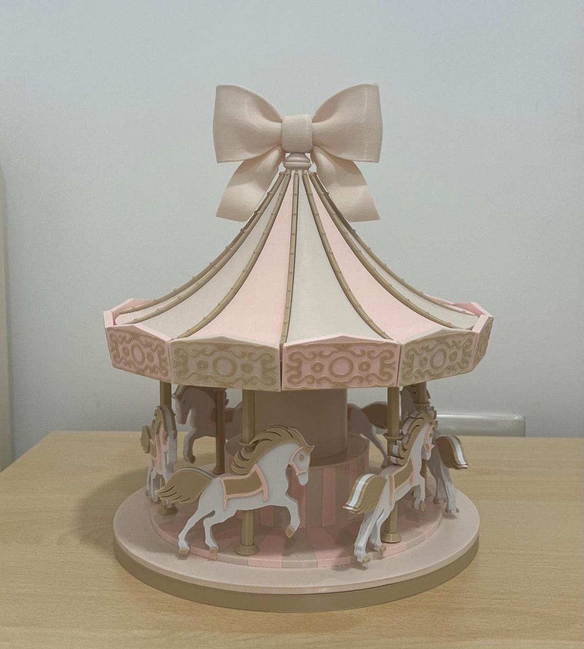 Carosello decorativo 3D in PLA con cavallini, tetto a spicchi e fiocco, fotografato su un tavolo