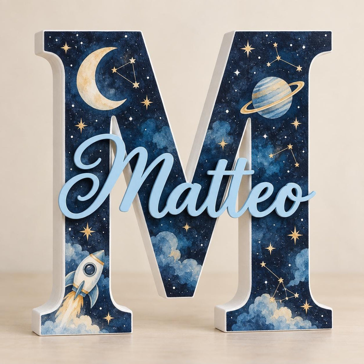 Lettera M con nome Matteo azzurro e tema spazio con luna, pianeta, stelle e razzo.