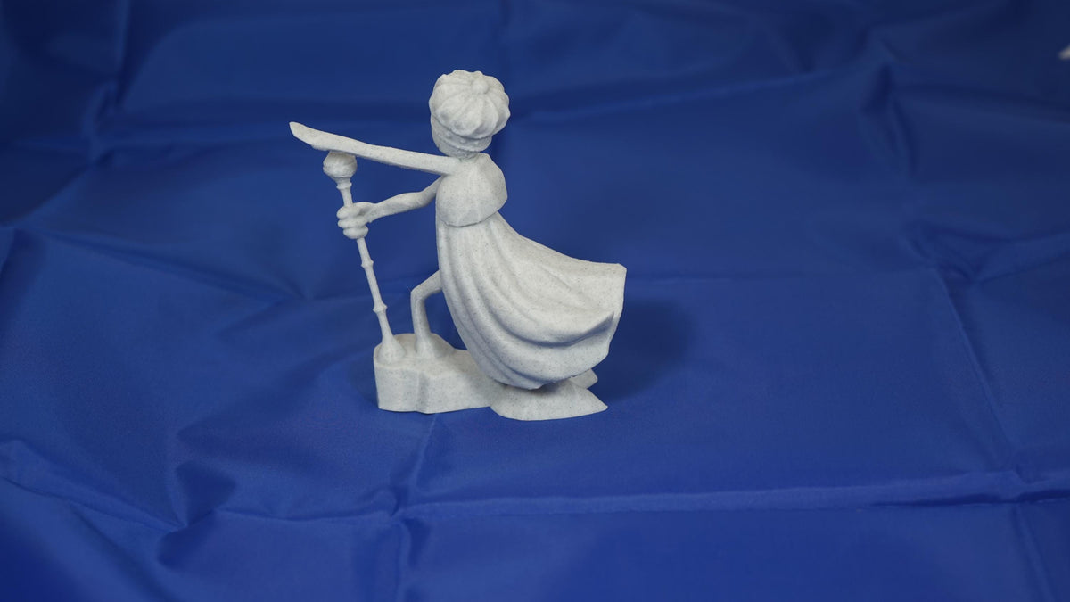 Statuetta fantasy chiara con mantello, spada e scettro su base rocciosa
