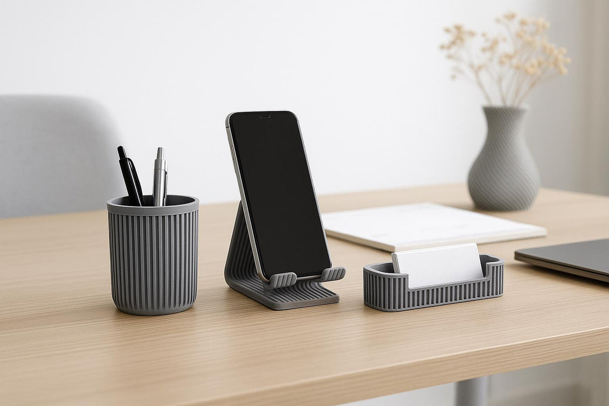 Portapenne, supporto smartphone e portabiglietti grigi ambientati su una scrivania in legno