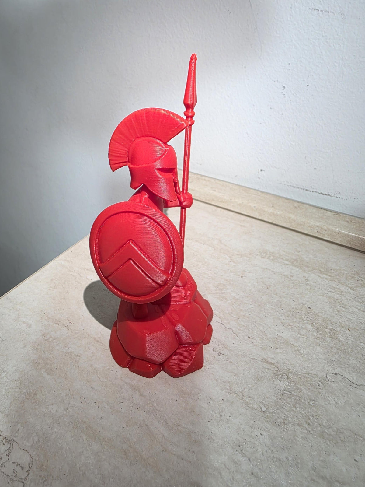 Statuetta Spartano rossa vista di lato, dettaglio dello scudo e dell'elmo