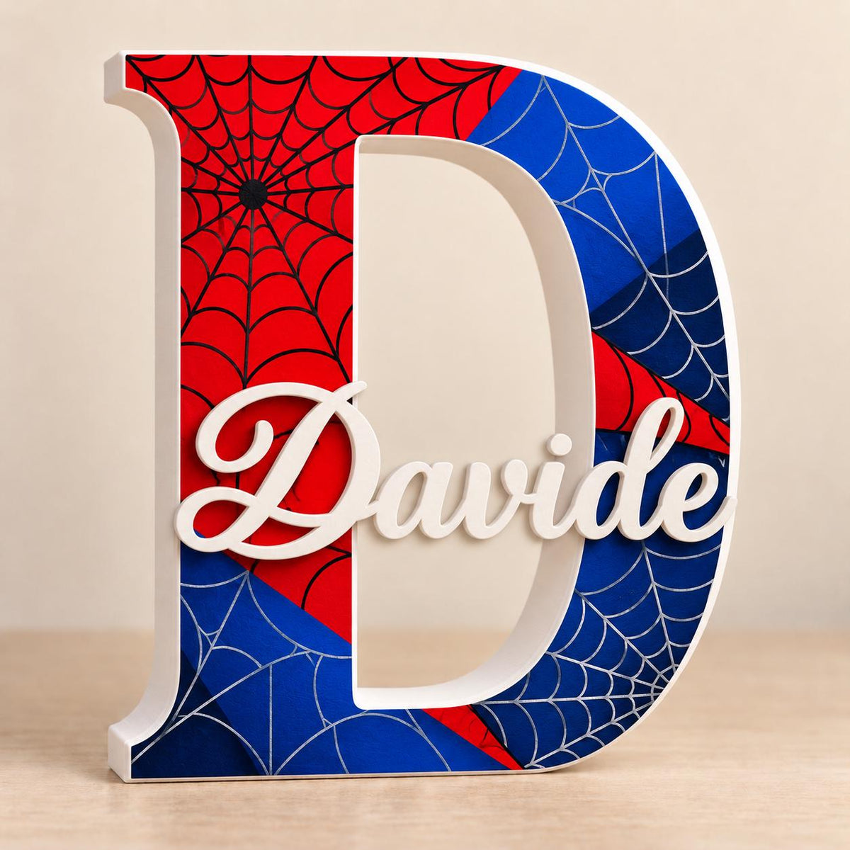 Lettera D con grafica di ragnatele rosse e blu e nome Davide bianco in rilievo.