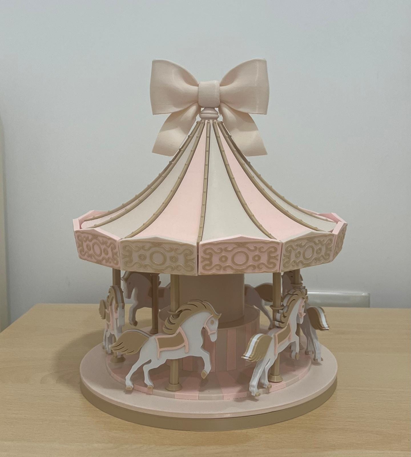 Carosello decorativo 3D in PLA con cavallini, tetto a spicchi e fiocco, fotografato su un tavolo