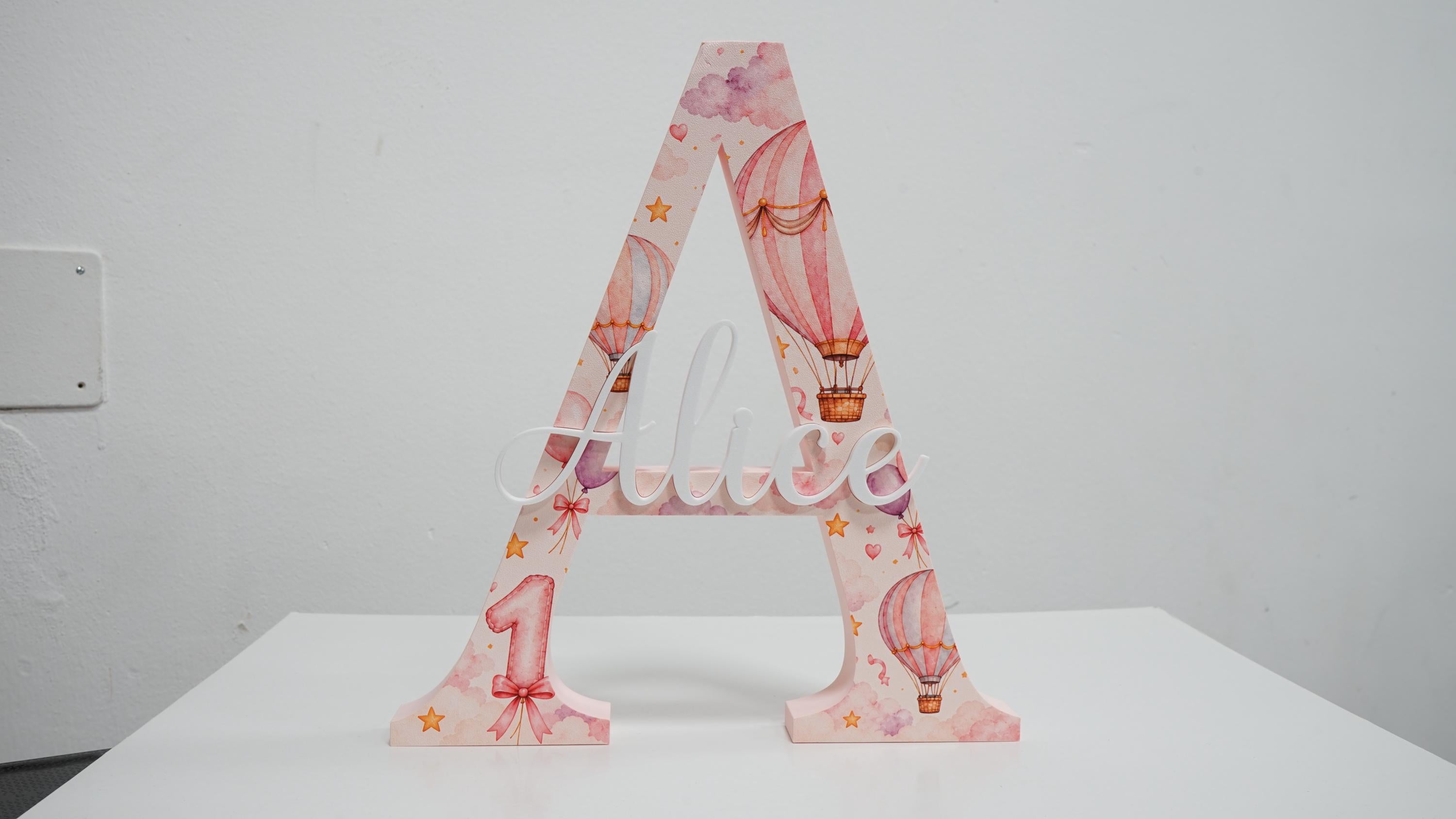 Lettera A da appoggio con nome Alice in rilievo, stampa UV con mongolfiere rosa e numero 1.